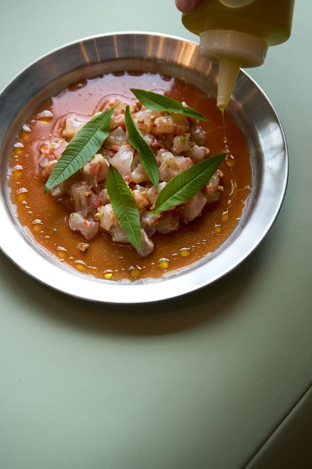 Ceviche with verbena leaves and olive oil on a metal plate