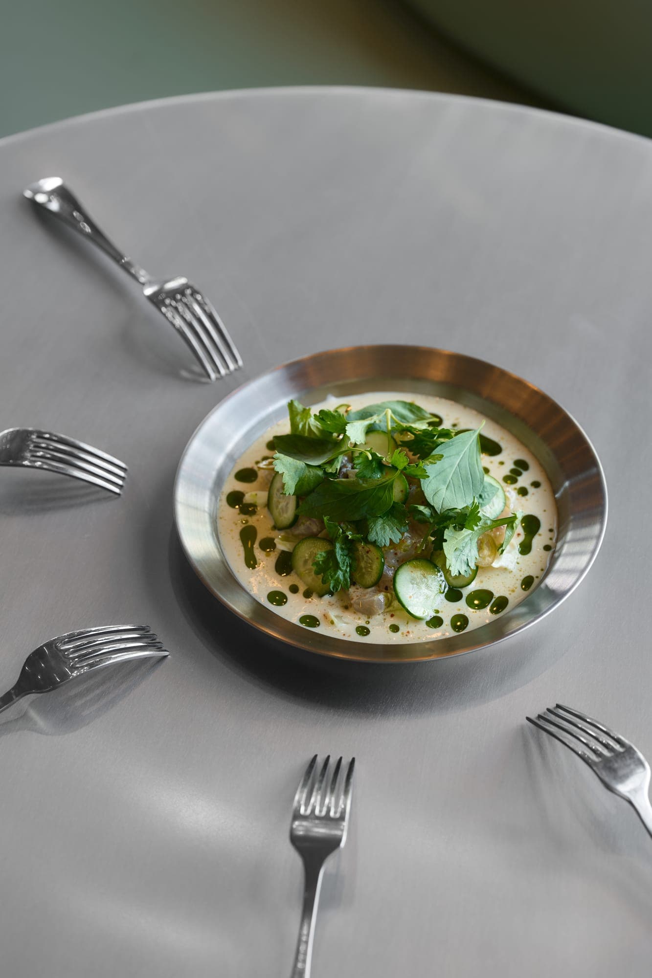 Creamy small plate topped with herbs and cucumber