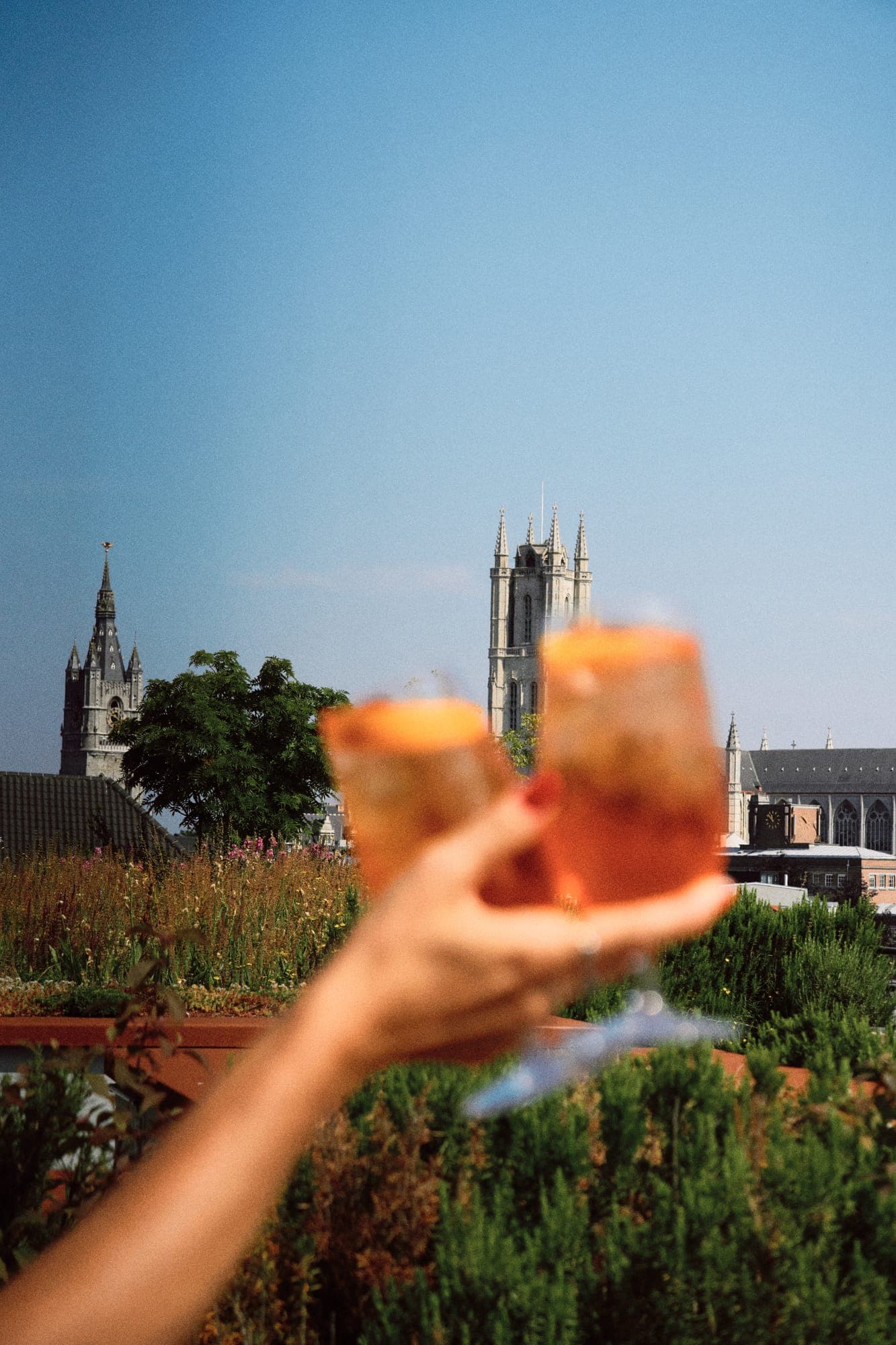 Spritz cocktail held up against the Ghent skyline