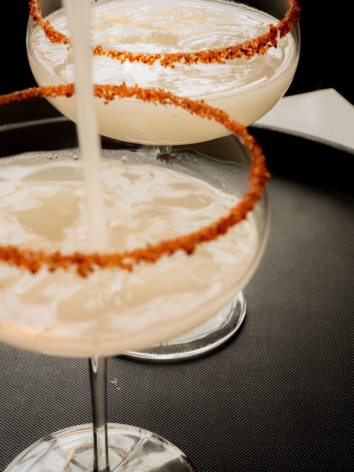 Cocktail poured into a coupe with a chili-salt rim
