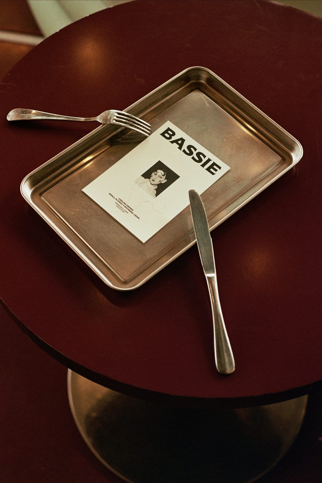BASSIE-branded card on a silver tray with cutlery